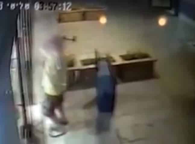 הפורץ מכה בפטיש בחלון הראווה של החנות